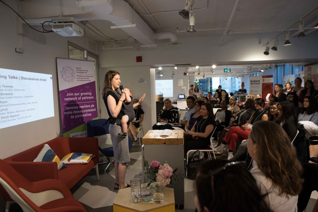 Amy Maureen Lynch speaking at the launch of the WEKH in Ontario in June 2019 at Impact Hub Ottawa while babywearing her son.